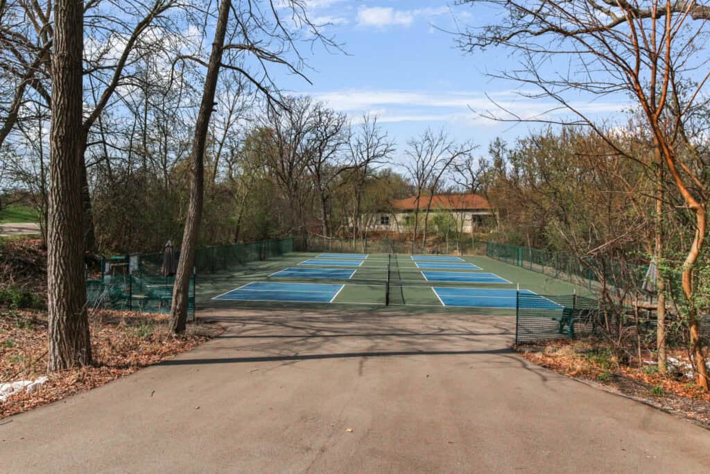 Tennis courts at Lake Geneva with scenic trees and clear skies, perfect for outdoor sports and recre.