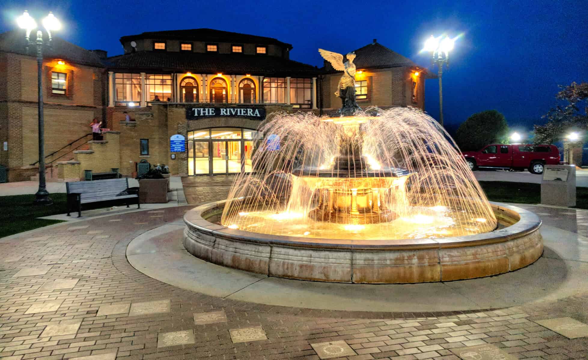 Night view of The Riviera fountain at Lake Geneva with illuminated water feature.