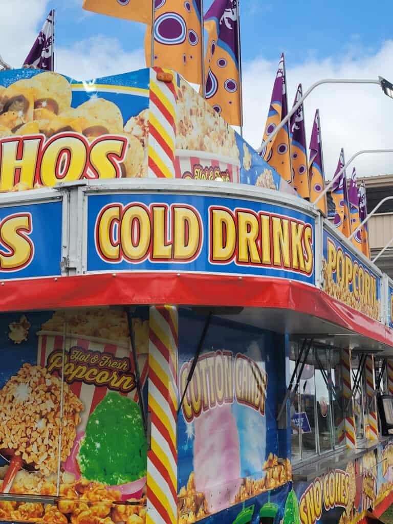 Colorful fair food stalls at Lake Geneva with popcorn and cold drinks.