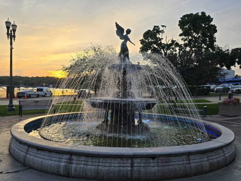 Scenic fountain with angel sculpture at Lake Geneva during sunset.
