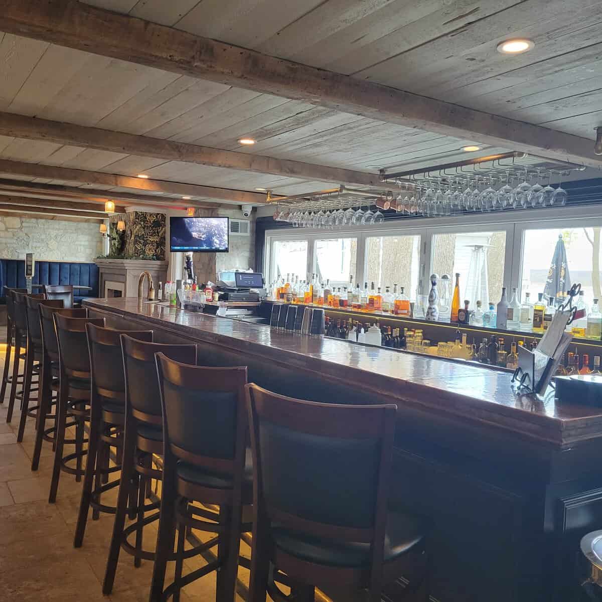 The Getaway's bar with stone walls, navy booths and windows facing Lake Como
