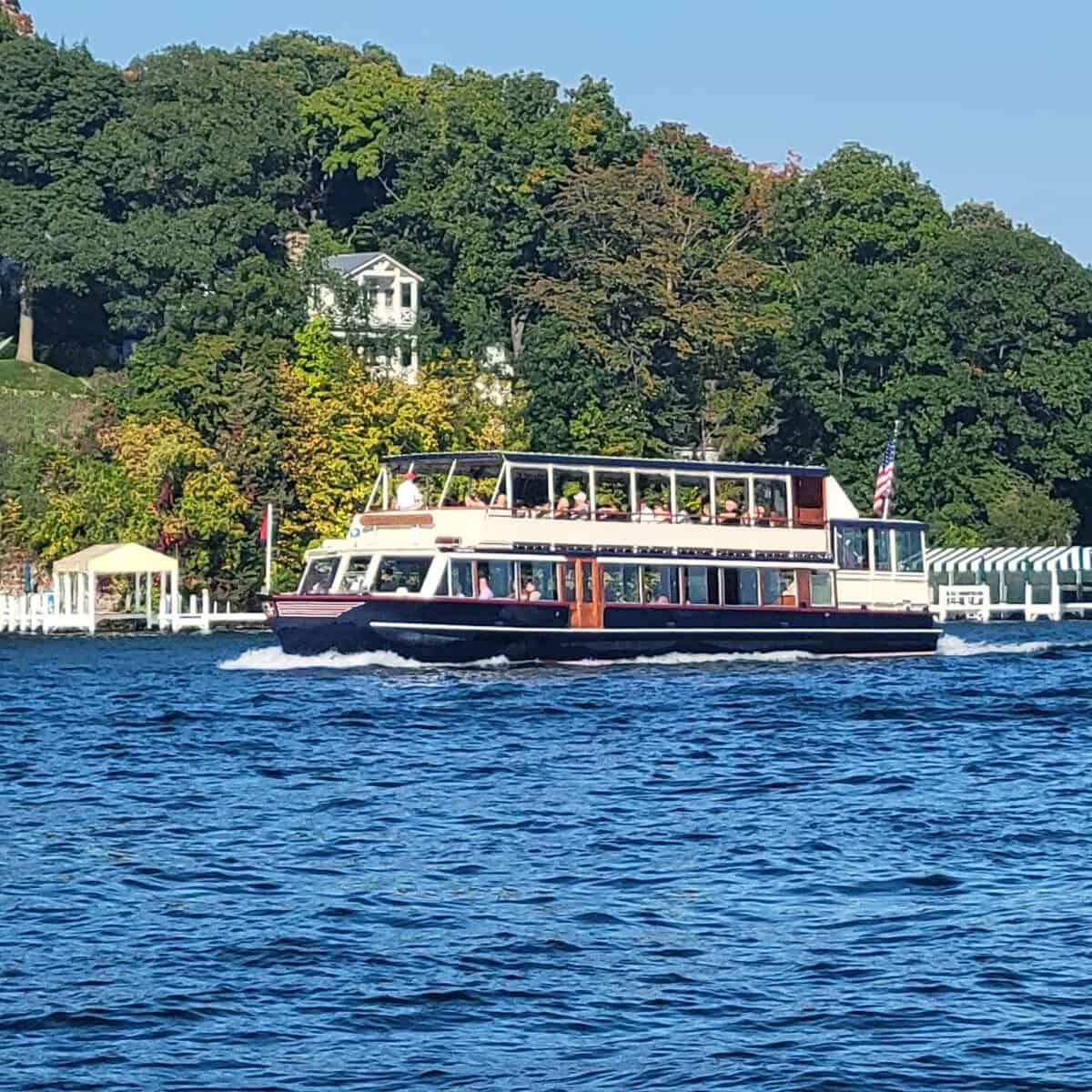The U.S. Mailboat cruising past a lakefront estate and boathouse on Geneva Lake