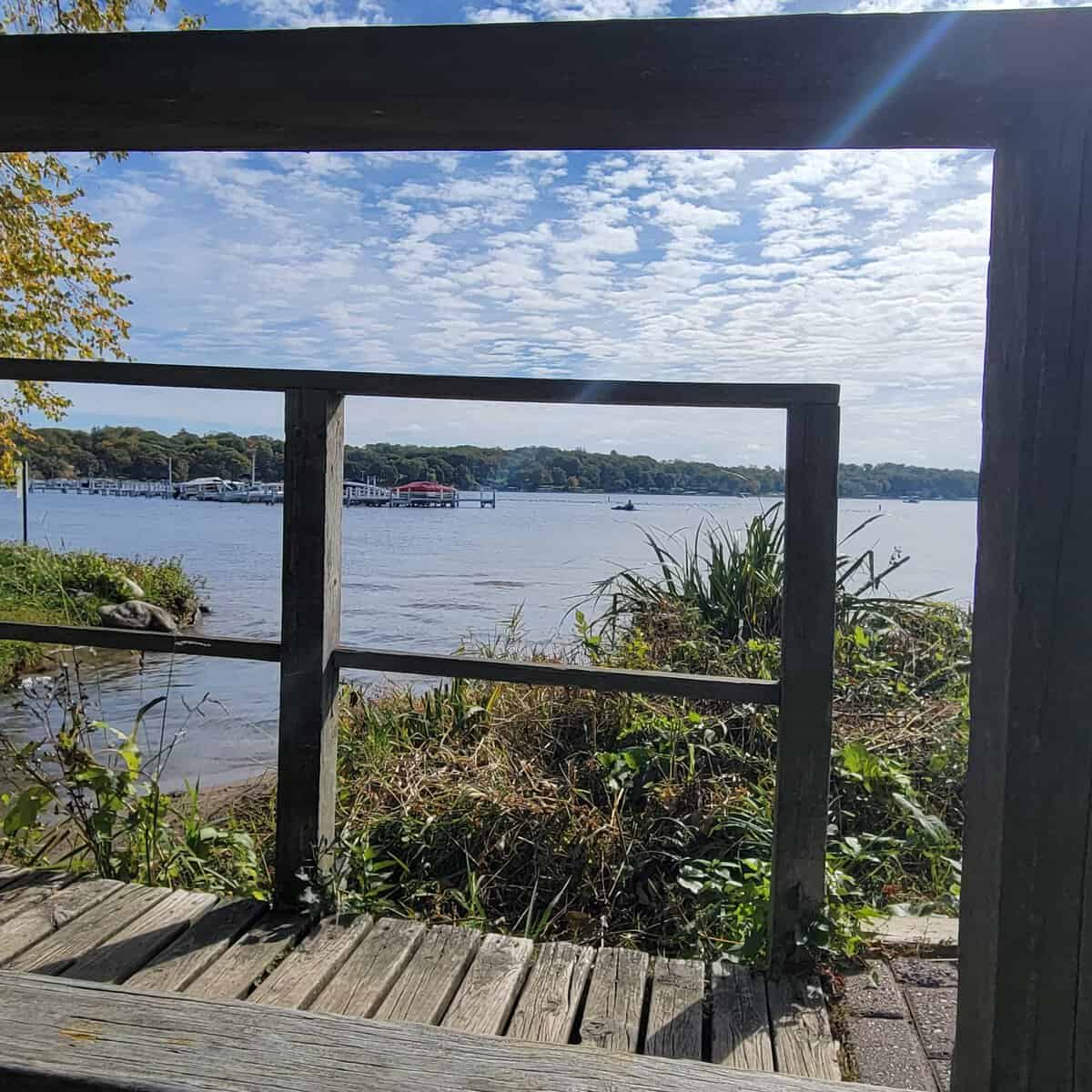Scenic view of Lake Geneva through a wooden railing on a sunny day.