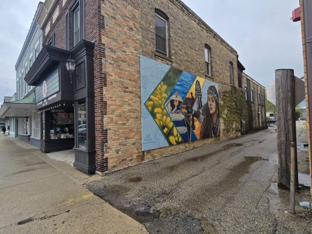 Colorful mural on brick building in Lake Geneva featuring a woman and scenic elements.