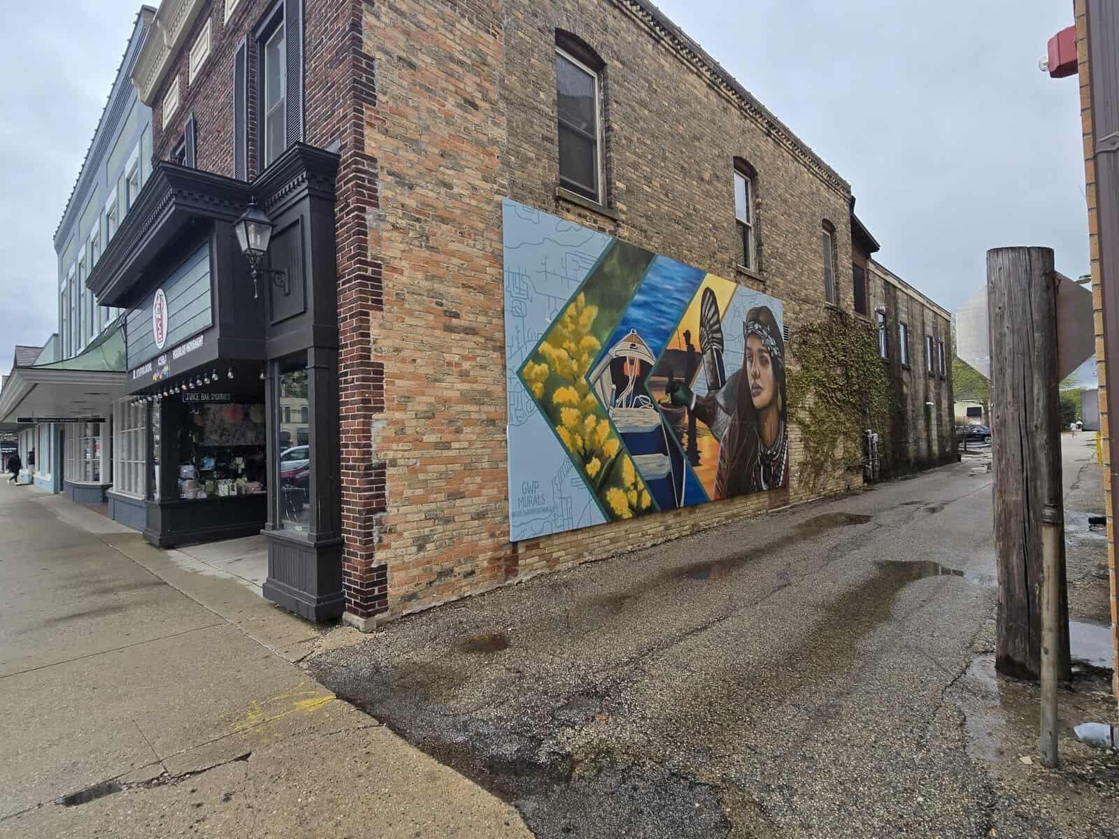 Colorful mural on brick building in Lake Geneva featuring a woman and scenic elements.