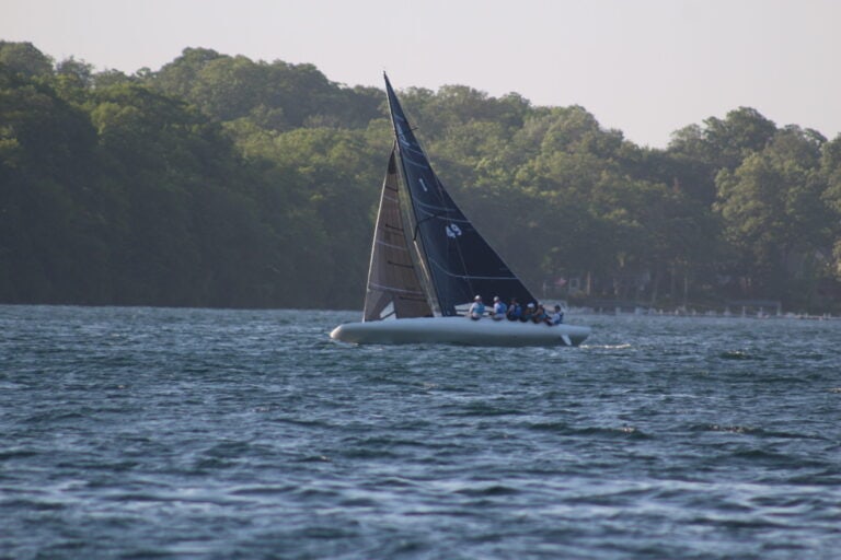 Sailboat with black sails on Lake Geneva during fall.