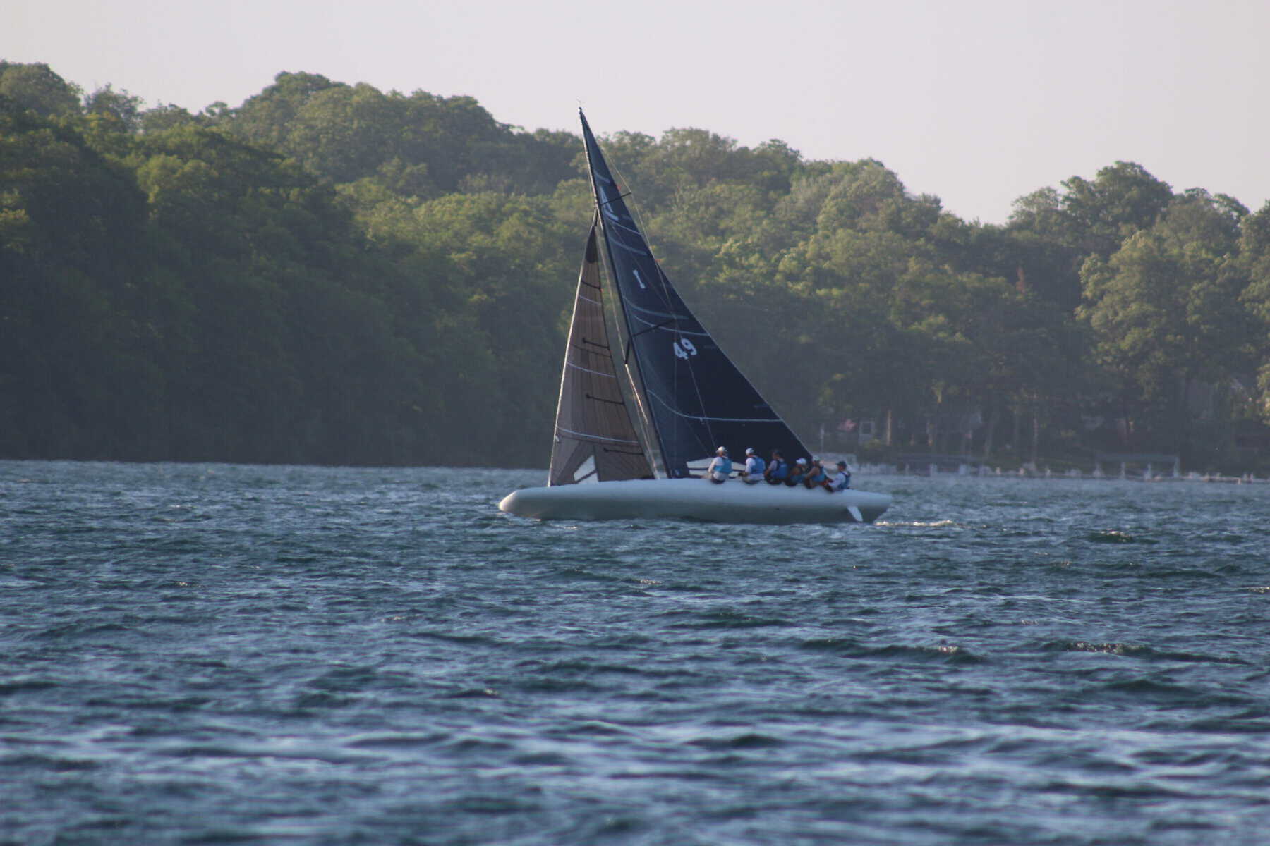 Sailboat with black sails on Lake Geneva during fall.