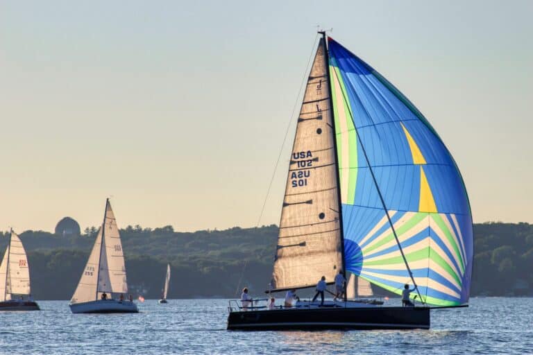 Sailboats with colorful spinnaker sails on Lake Geneva during sunset.